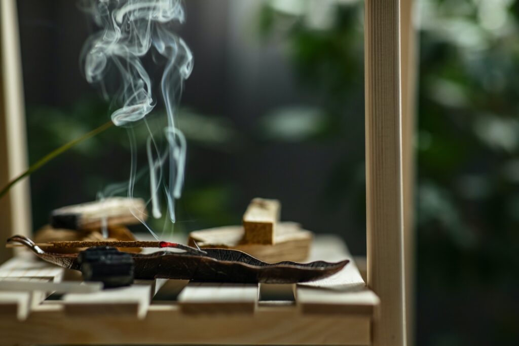 magical smoke from a burning incense stick on an incense stand on a wooden shelf in the interior
